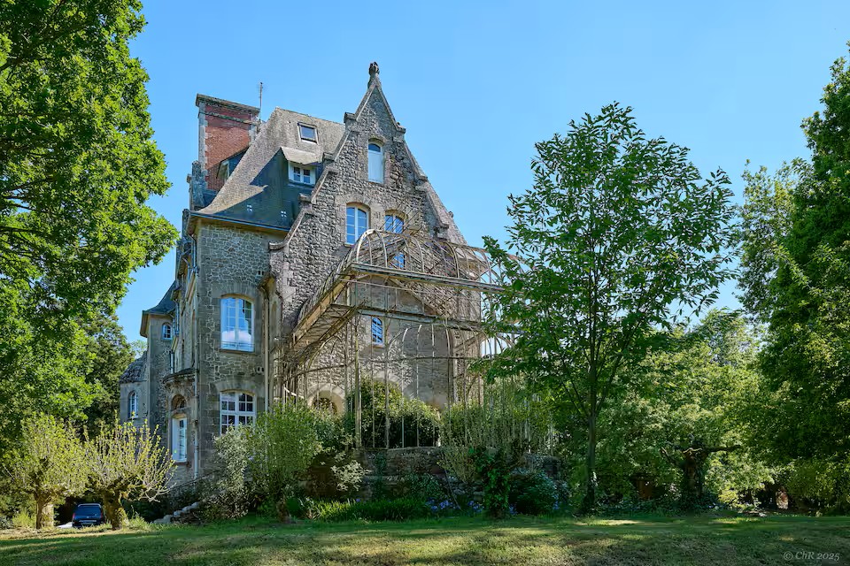 Le pignon du château et son ancienne serre, entre les arbres