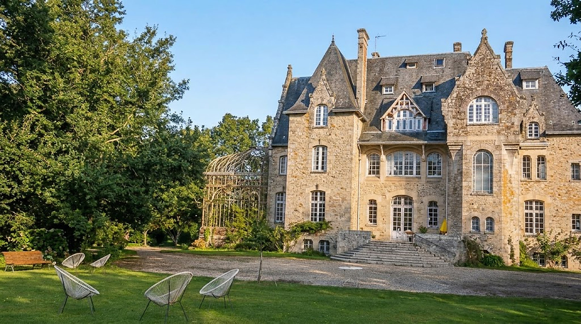 La façade du château Beauregard, sa pelouse et ses fauteuils sous le ciel bleu de Bretagne